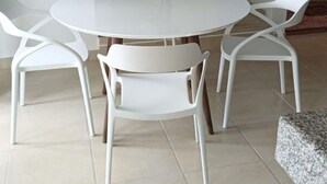 Een ronde eettafel met vier witte stoelen.