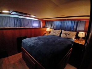 Een slaapkamer met een groot bed, twee bedlampen, een raam met gordijnen en een wandairconditioner.