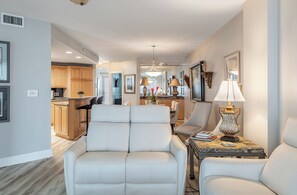 A modern living room with a sofa, a side table with a lamp, and a dining area in the background. - Olde Towne Yacht Club 512 (Beaufort)