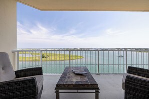 Een balkon met uitzicht op een waterpartij, een gazon en een verre kustlijn.