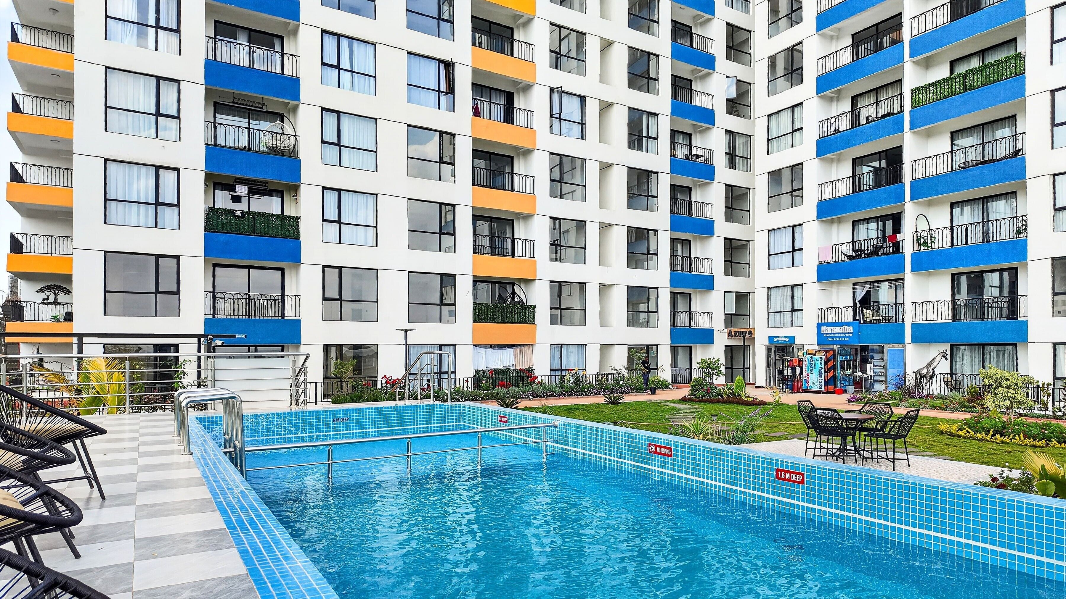 A multi-story hotel with a swimming pool, balconies, and outdoor seating.