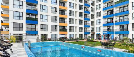 A multi-story hotel with a swimming pool, balconies, and outdoor seating.