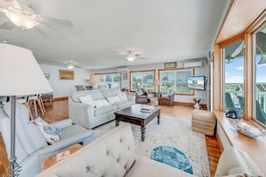 A spacious living room with a sofa, armchair, and ottoman, a coffee table, and a ceiling fan. - Amazing BAY VIEWS at Moon Fish by Seaside Vacations! (Chincoteague Island)