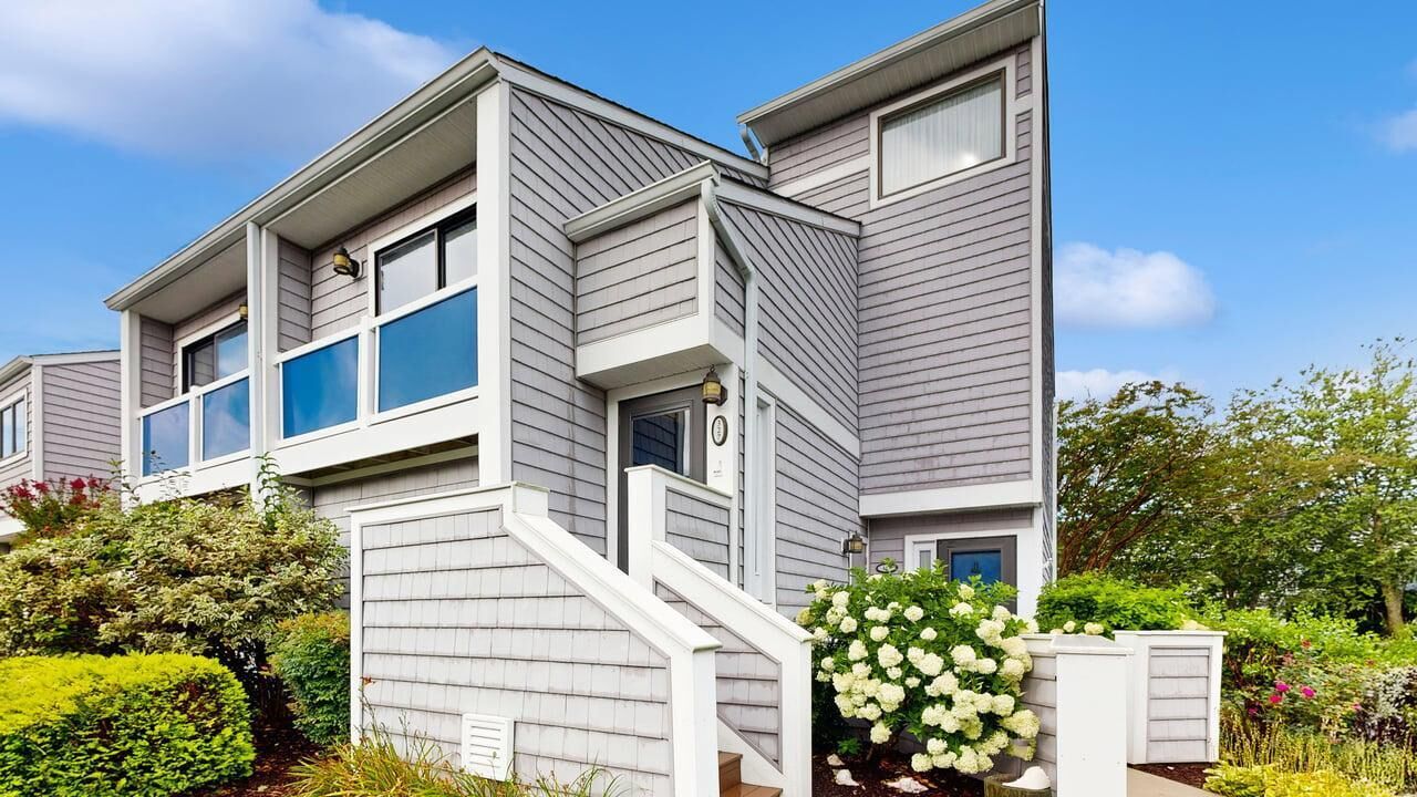 A two-story residential building with a modern design, featuring a prominent staircase and a well-maintained garden with various plants and flowers.
