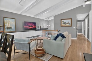 Una sala de estar moderna con sofá, sillón, mesa de centro y un cuadro en la pared.