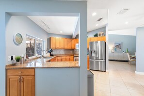 Une cuisine moderne avec des meubles en bois, un réfrigérateur en acier inoxydable et un plan de travail en granit.