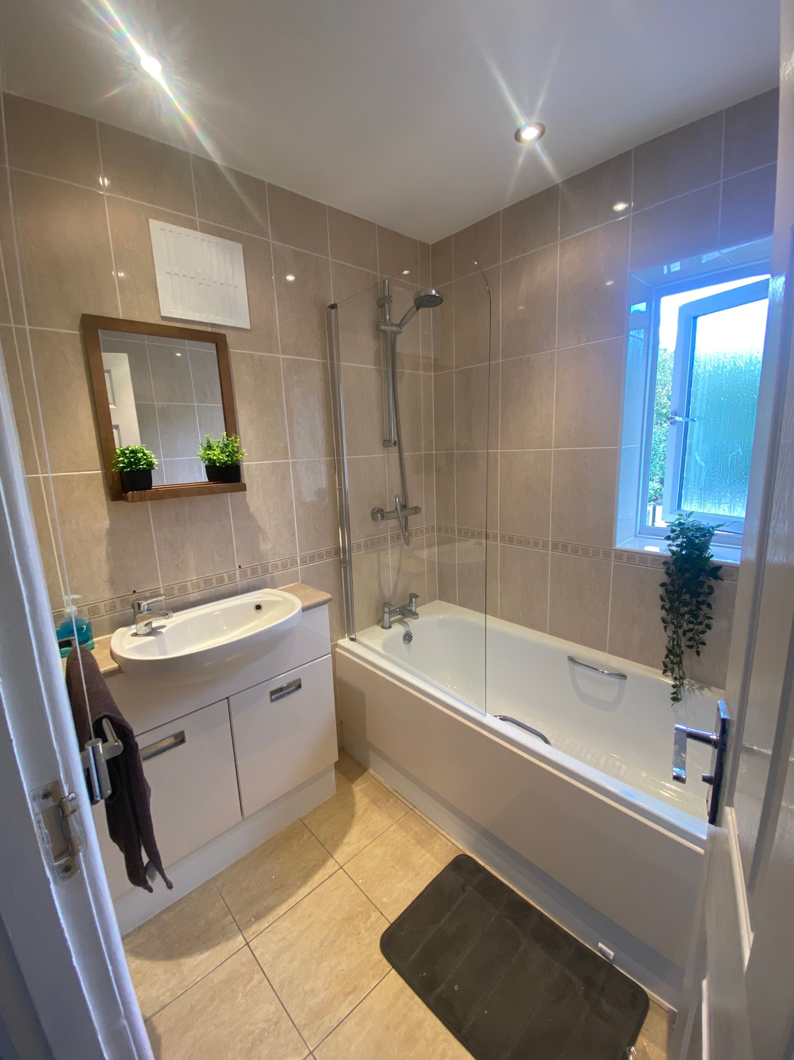 Un baño moderno con bañera, ducha, lavamanos y espejo.