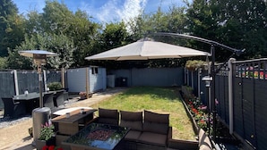 A backyard with a patio area, outdoor furniture, a barbecue grill, and a covered seating area. - House Sleeps 4- Free Parking, Garden, Pet Friendly (Bournemouth)