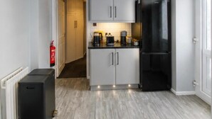 A compact kitchen with white cabinets, a black refrigerator, and a coffee maker on the counter. - House Sleeps 4- Free Parking, Garden, Pet Friendly (Bournemouth)