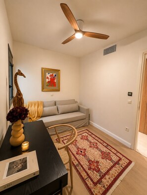 A living room with a ceiling fan, a sofa, a coffee table with a vase and candle, and a patterned rug. - ELAIA Luxury Voula Residence with Private Pool on Athens Riviera (Voula)