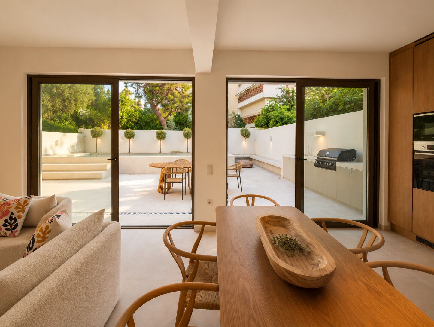 Un interior moderno con comedor, cocina con parrilla y vista a un patio exterior.