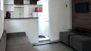 A modern living room with a sofa, a TV, and a ceiling fan. - BEST VIEW OF BICA BEACH (Rio de Janeiro)