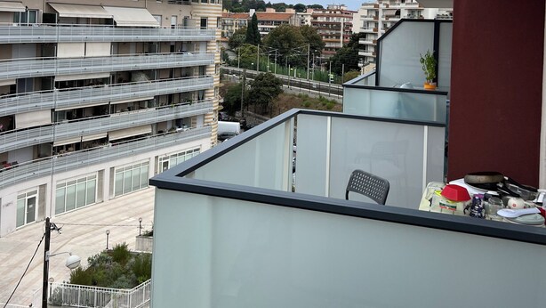 A multi-story residential building with balconies, a street view, and a distant hill. - Detached studio apartment across from Riquier Station, with a beautiful view of the hills of Nice (Nice)