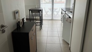 A compact kitchen with a dining table and chairs, a built-in oven, and a view through a glass door. - Detached studio apartment across from Riquier Station, with a beautiful view of the hills of Nice (Nice)