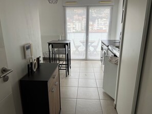 Eine kompakte Küche mit Esstisch und Stühlen, einem eingebauten Backofen und Blick durch eine Glastür.