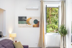 A room with a window, a radiator, a wall-mounted air conditioner, a lamp, a cushion, and a plant. - The Golden Rooster -1 min to the station (Roma)