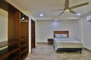 A bedroom with a bed, a wooden wardrobe, a ceiling fan, and a small bedside table. - Casa Tranquilidad 3-bed by Island House Vacation Rentals (West Bay)