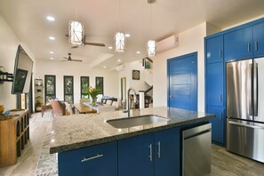 A modern kitchen with blue cabinets, a stainless steel refrigerator, and a granite countertop. - Casa Tranquilidad 3-bed by Island House Vacation Rentals (West Bay)