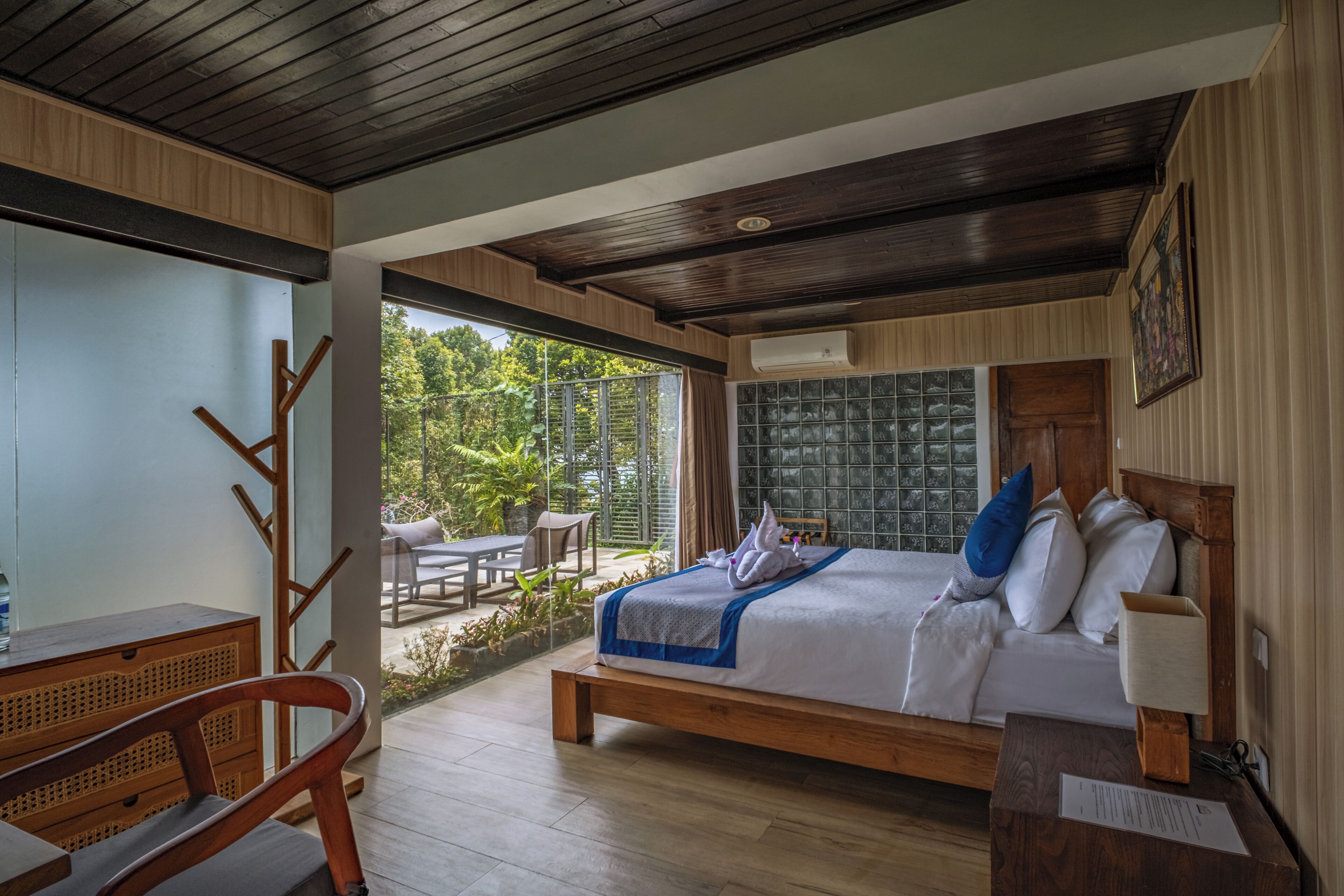 A bedroom with a bed, a desk, and a view of the outdoors.