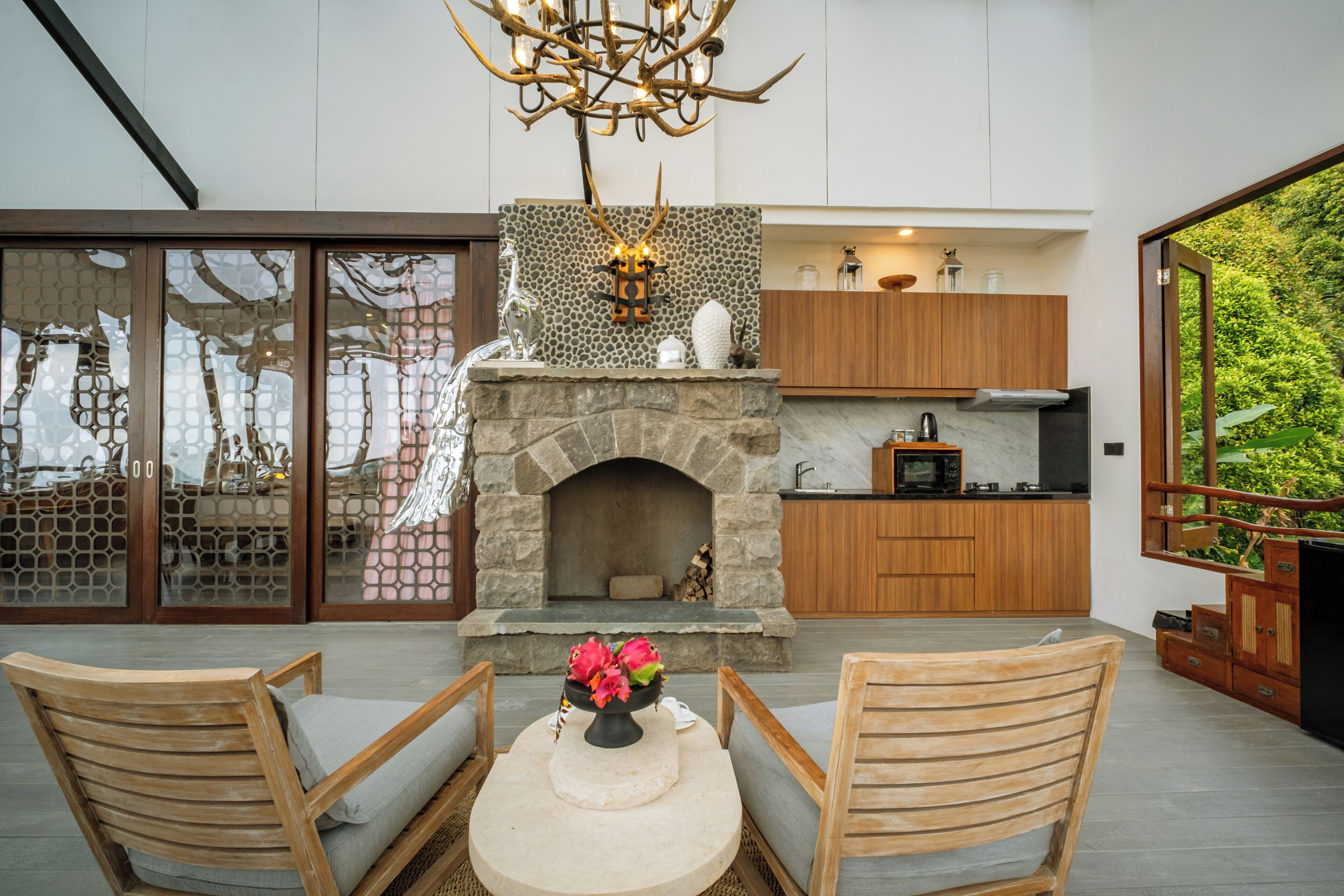 An outdoor kitchen area with a stone fireplace, wooden cabinets, and a dining table with chairs.