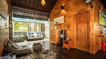 A cozy interior with a wooden ceiling, a sofa with patterned cushions, a coffee table, and a decorative wall piece.