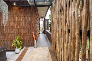 A corridor with wooden walls, a potted plant, and a pathway leading to a door. - Munduk Harvest Palace (Munduk)