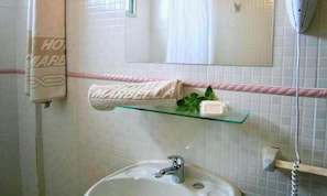 A bathroom with a sink, mirror, towel rack, and a glass shelf with toiletries. - Hotel Marbella (Punta del Este)