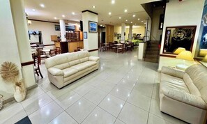 Un vestíbulo de hotel con un sofá, zona de comedor y una escalera.