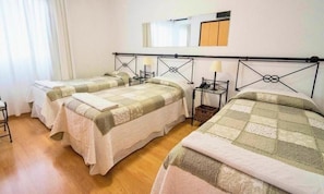 A hotel room with three beds, a wooden floor, and a mirror on the wall. - Hotel Marbella (Punta del Este)