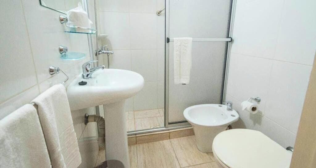 A bathroom with a glass shower enclosure, a sink, a toilet, and a towel rack.