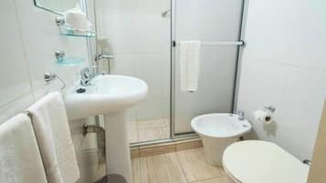 A bathroom with a glass shower enclosure, a sink, a toilet, and a towel rack.