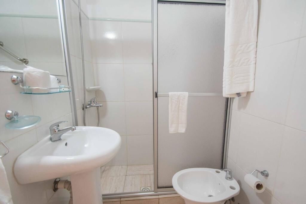 Un baño con cabina de ducha de vidrio, lavamanos, bidé y retrete.