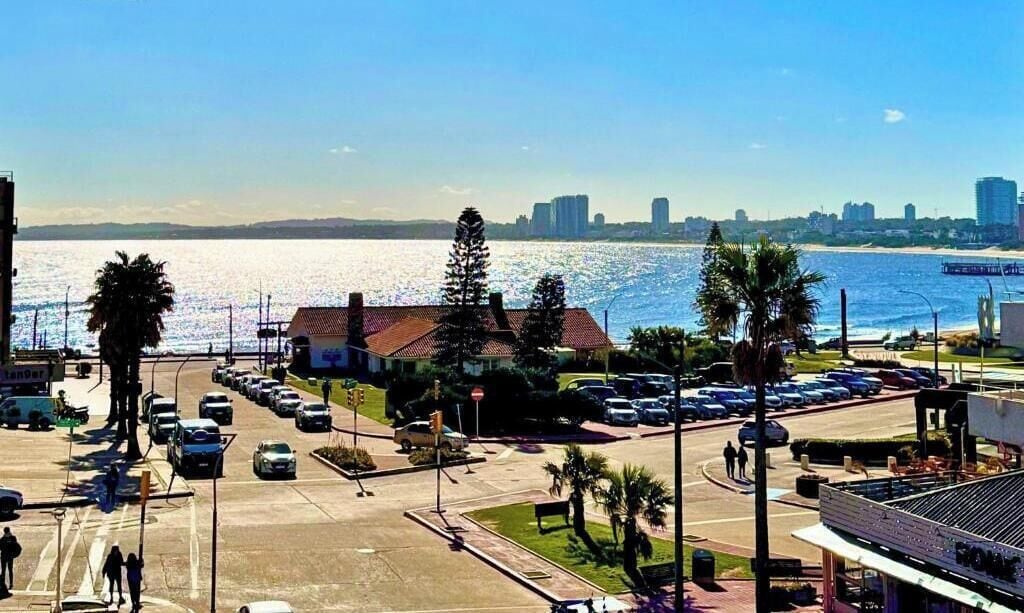 Paisaje costero urbano con un estacionamiento, edificios y vista al mar.