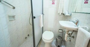 Un baño con ducha, inodoro, lavamanos y toallero.