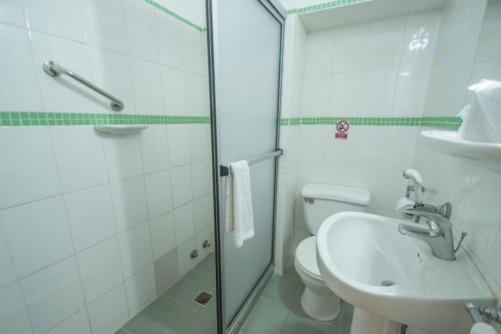A bathroom with a glass-enclosed shower, a toilet, and a sink.