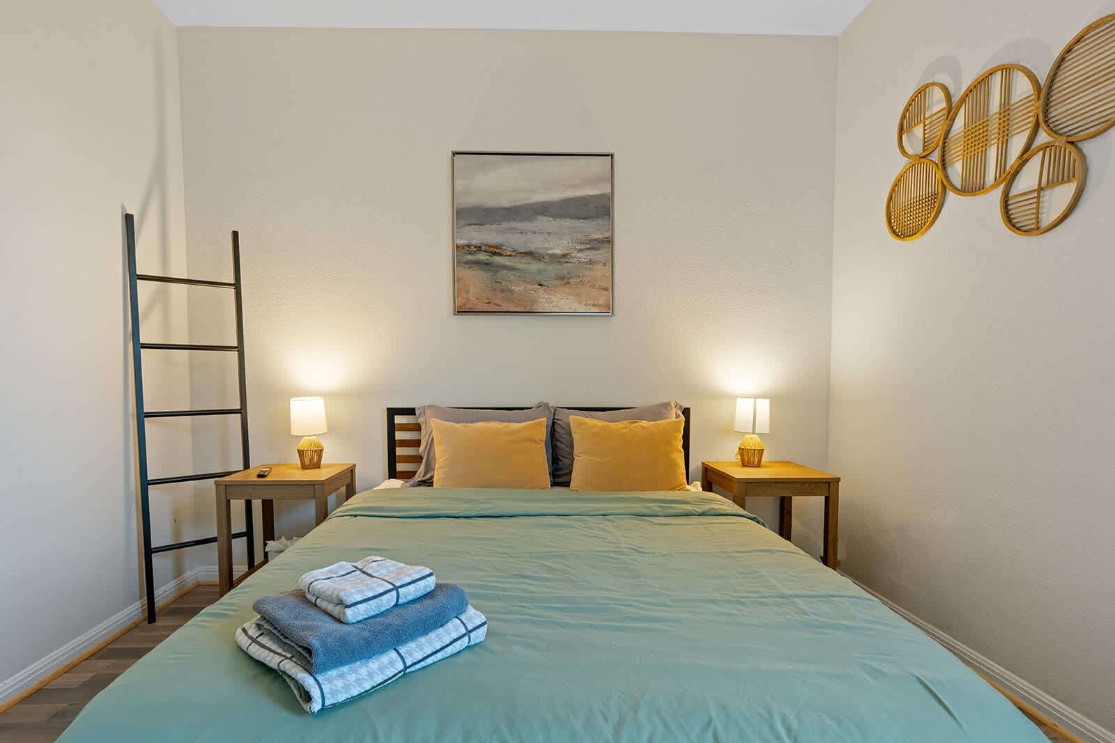 Une chambre d’hôtel avec un lit, deux lampes de chevet, un tableau et un élément de décoration murale.
