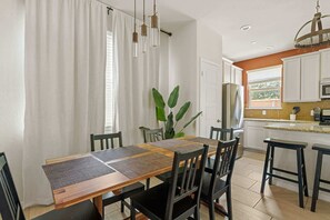 A dining area with a wooden table, black chairs, and a plant.