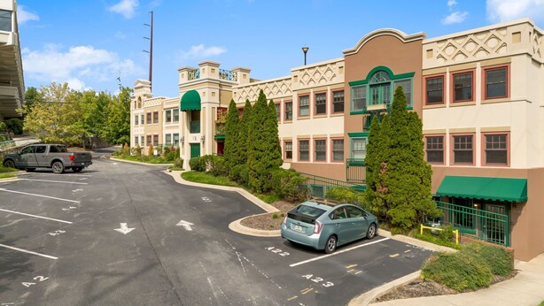 A parking lot with marked parking spaces, a building with a green awning, and a car parked in front. - Walkable Downtown Asheville Retreat | Inc. Biltmore Pass & Dog Friendly (Asheville)