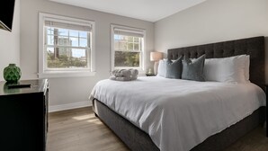 A bedroom with a bed, two windows, a bedside table, and a lamp. - Walkable Downtown Asheville Retreat | Inc. Biltmore Pass & Dog Friendly (Asheville)