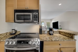 A modern kitchen with a stainless steel stove, microwave, and coffee maker. - Walkable Downtown Asheville Retreat | Inc. Biltmore Pass & Parking (Asheville)