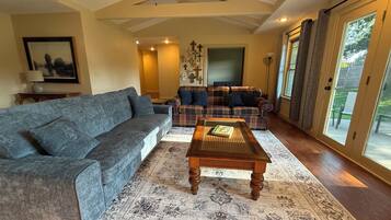 A living room with a gray sofa, a plaid sofa, a wooden coffee table, and a patterned rug.