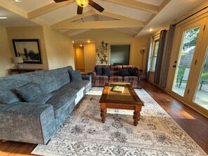 A living room with a gray sofa, a plaid sofa, a wooden coffee table, and a patterned rug.