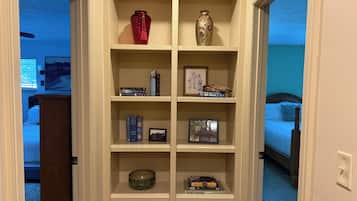 A room with a bed, a desk, and a bookshelf containing books and decorative items.