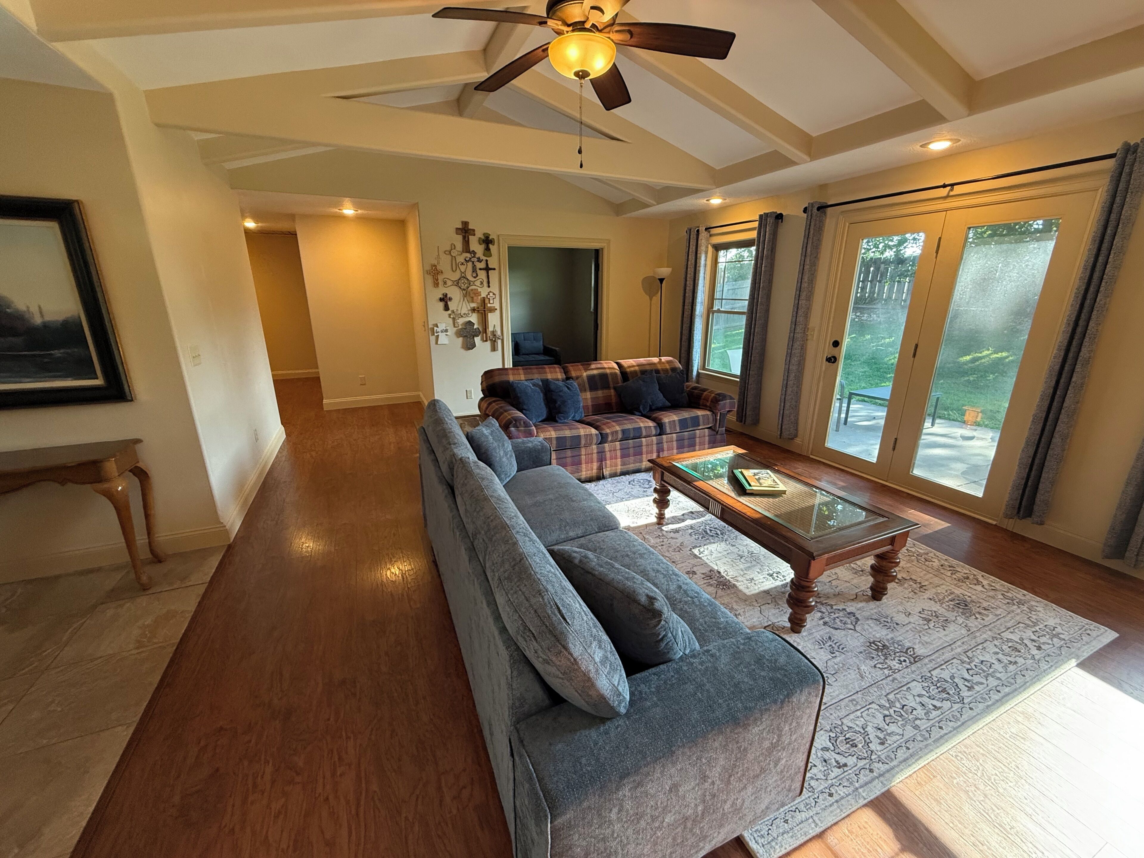 A spacious living room with a large sofa, a coffee table, and a ceiling fan.