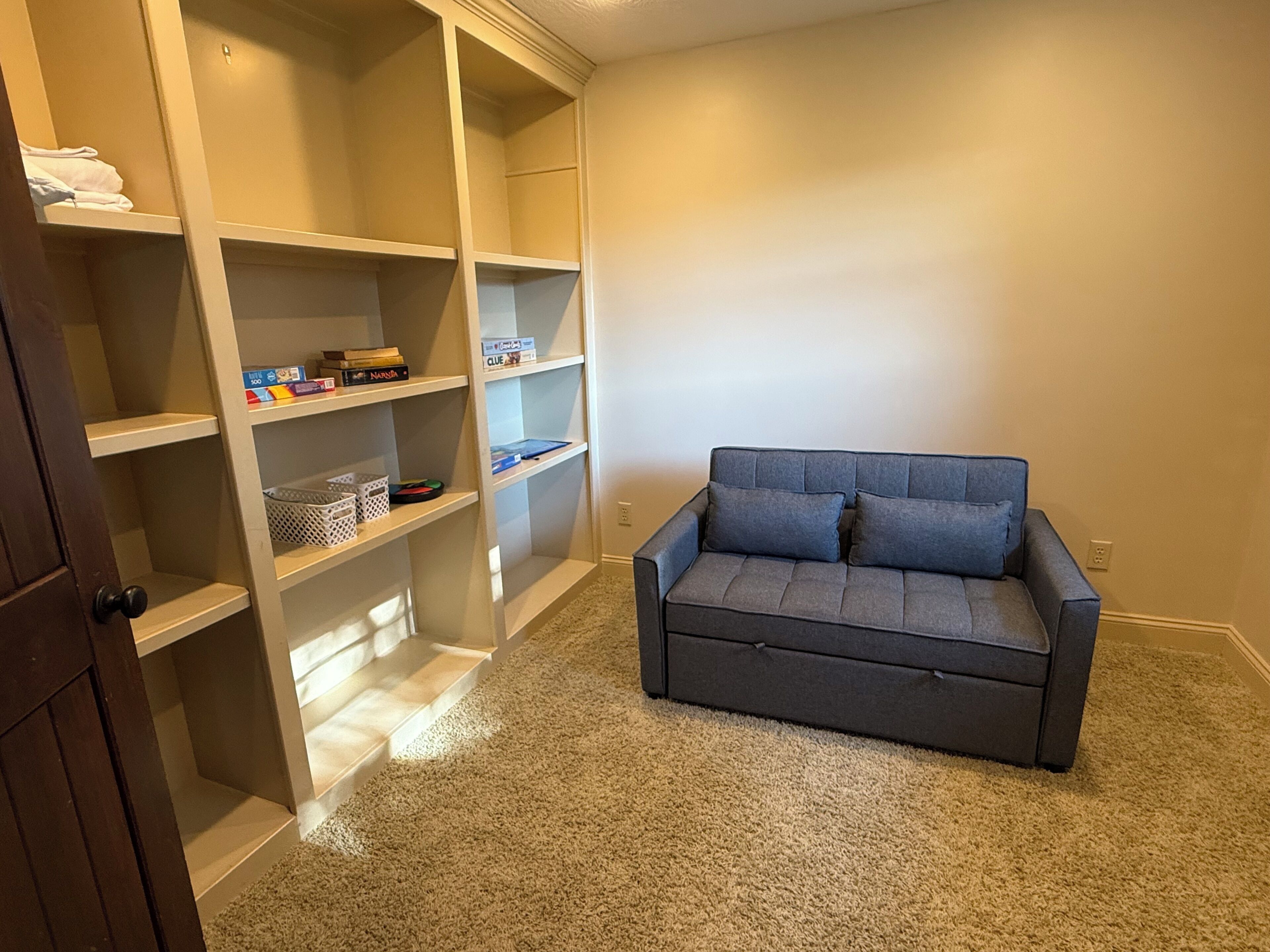 A room with a grey sofa and a built-in shelving unit against a wall.