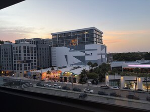 A modern building with a geometric facade, a parking lot with several cars, and a street view with a restaurant. - Nomad Wynwood - Boutique luxury 1 bedroom+Den+2B (Miami)
