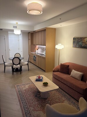 A modern living room with a sofa, a coffee table, a rug, and a dining area with chairs and a table. - Nomad Wynwood - Boutique luxury 1 bedroom+Den+2B (Miami)
