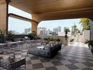 A rooftop terrace with outdoor seating, a checkered floor, and a view of the city skyline. - Nomad Wynwood - Boutique luxury 1 bedroom+Den+2B (Miami)