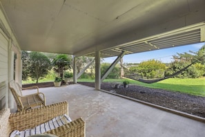 A covered porch with outdoor seating, a hammock, and a view of a grassy area with trees. - Heron Marsh 108 Beautiful view, Litchfield by the Sea (Pawleys Island)