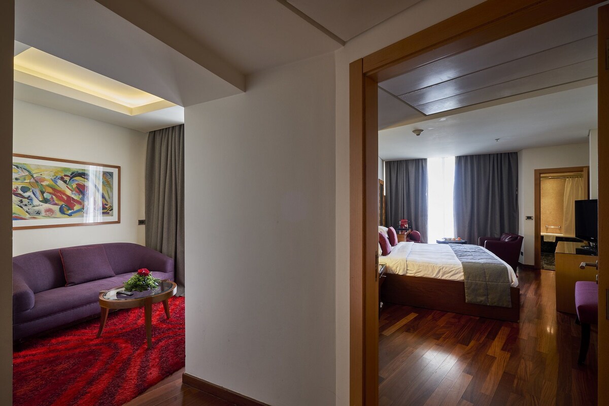 Une chambre d’hôtel avec un canapé, un lit, une télévision et un tableau au mur.